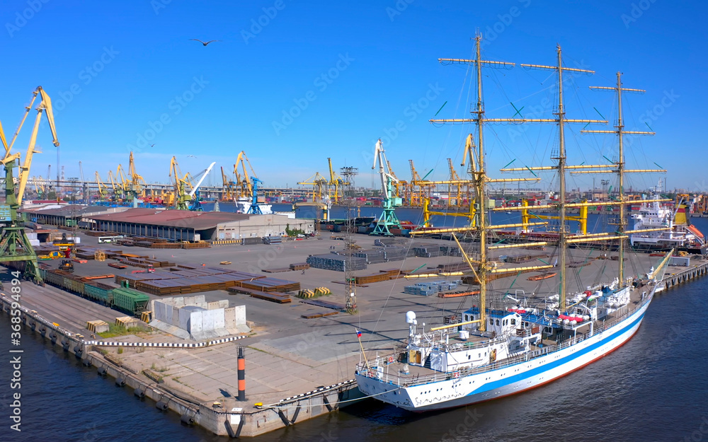 Aerial view of a row of construction or cargo cranes on the river bank with a boat sailing nearby.