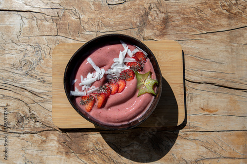 Fruit smoothie bowl with strawberries on wooden background, raw vegan diet