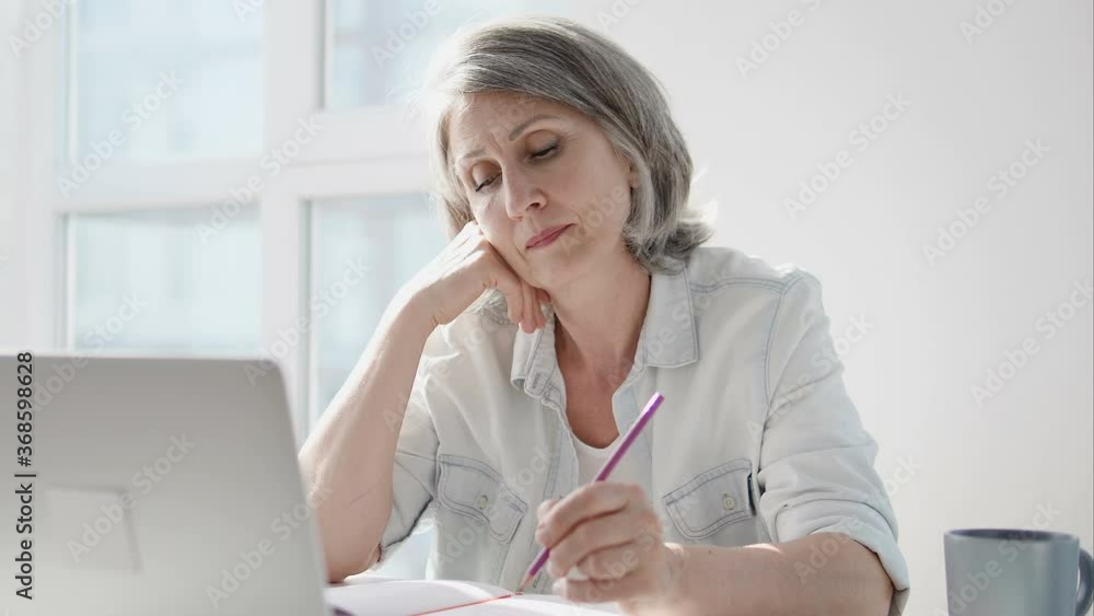 Senior woman sitting at table, drawing in notepad, creative leisure, freelance Senior woman sitting at table, drawing in notepad, creative leisure, freelance