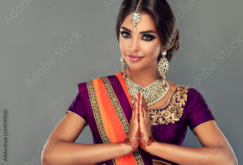 Фотография Portrait of a beautiful indian girl in a greetting pose to Namaste