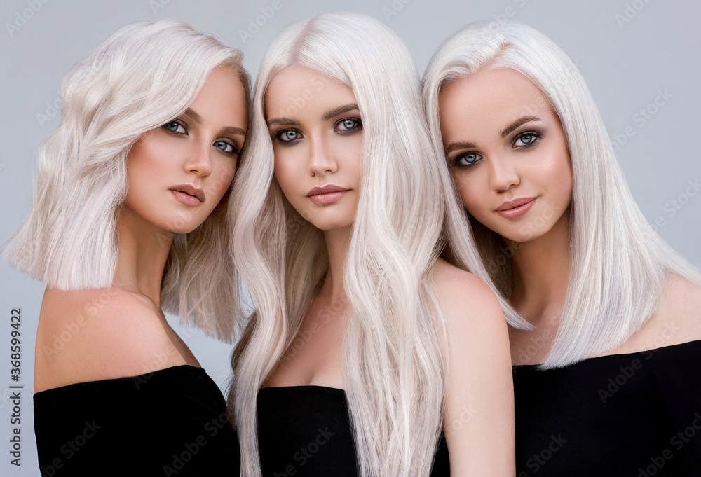 Three beautiful girls with hair coloring in ultra blond. Stylish hairstyle curls done in a beauty salon. Beauty, cosmetics and makeup - obrazy, fototapety, plakaty 