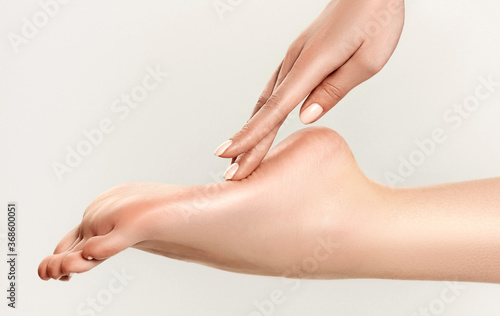 Perfect clean female foot . Beautiful and elegant groomed girl's hand touches her feet . Spa ,scrub and leg care . © Sofia Zhuravetc