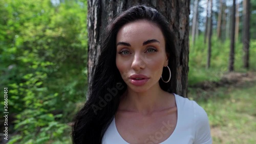 Woman standing against a tree and looking straight at the camera
