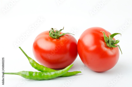 Closeup of green chili pepper, fresh juicy tomatos on the white background