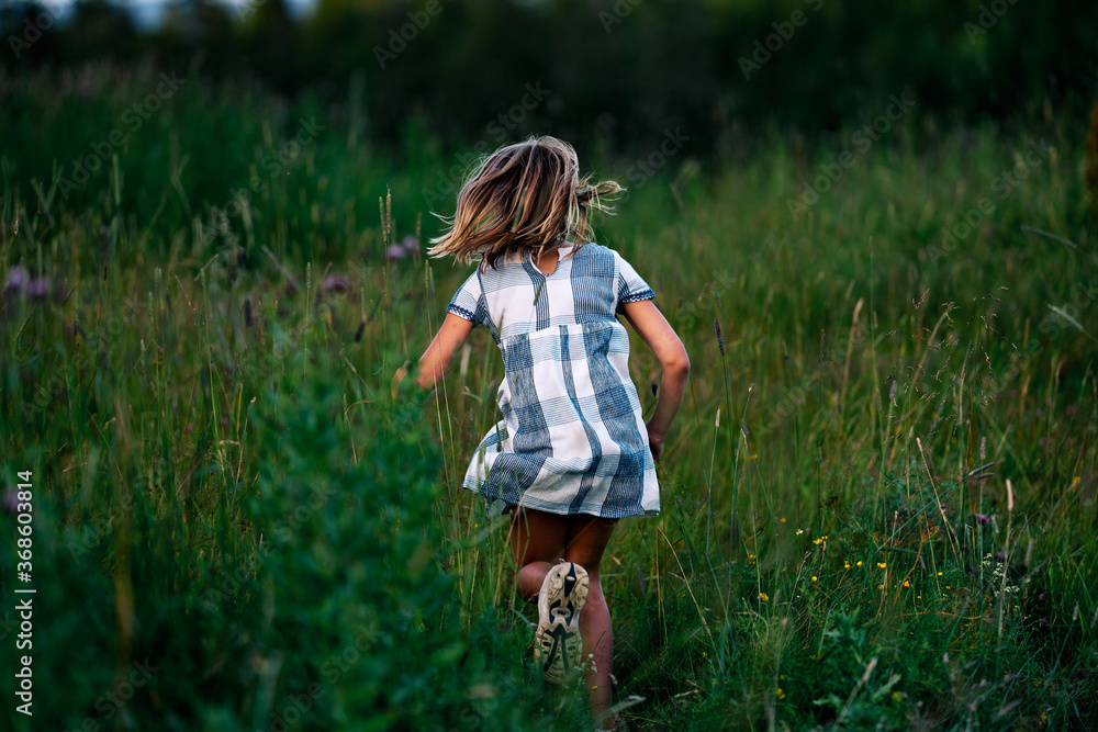 A girl chasing a butterfly in a flower meadow.  Shot at Holmenkollen, Oslo, Norway.