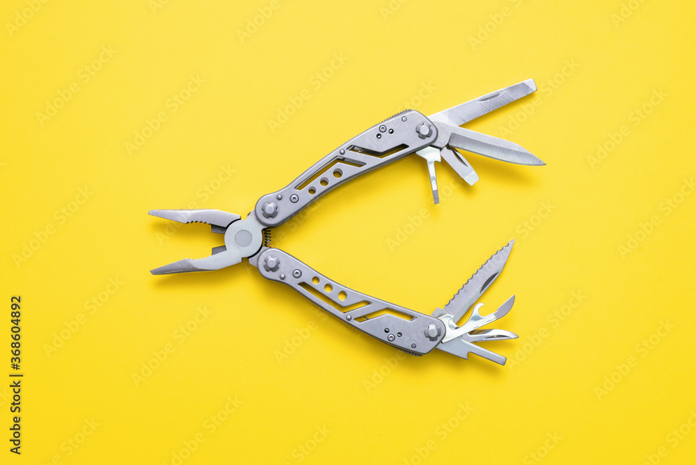 Steel multi tool on the yellow flat lay background. - obrazy, fototapety, plakaty 