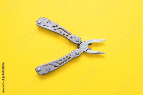 Steel multi tool on the yellow flat lay background.