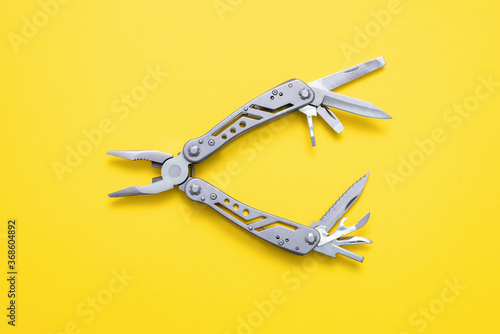 Steel multi tool on the yellow flat lay background. photo
