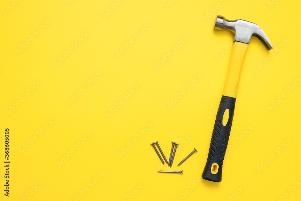 Hammer and heap of nails on the yellow flat lay background with copy space. Hammer and heap of nails on the yellow flat lay background with copy space.