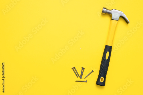 Hammer and heap of nails on the yellow flat lay background with copy space.