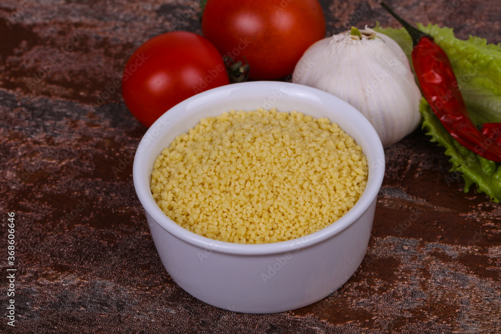 Raw couscous in the bowl served salad leaves, tomato and pepper Raw couscous in the bowl served salad leaves, tomato and pepper