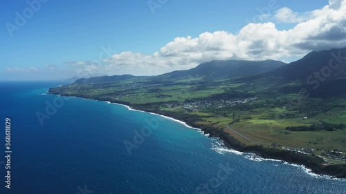 Bird's eye view of the blue sea, black coast, green fields and wooded mountains in Saint Kitts and Nevis