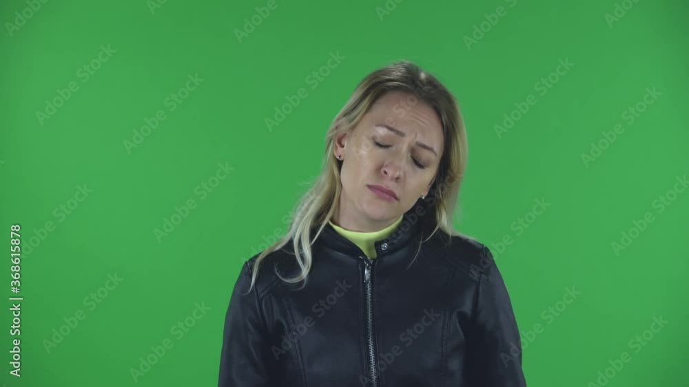 Portrait of beautiful young woman is looking straight . She has temperature is coughs and covers itself with an elbow. Blonde with loose hair in a black jacket and jeans on a green screen in the Portrait of beautiful young woman is looking straight . She has temperature is coughs and covers itself with an elbow. Blonde with loose hair in a black jacket and jeans on a green screen in the