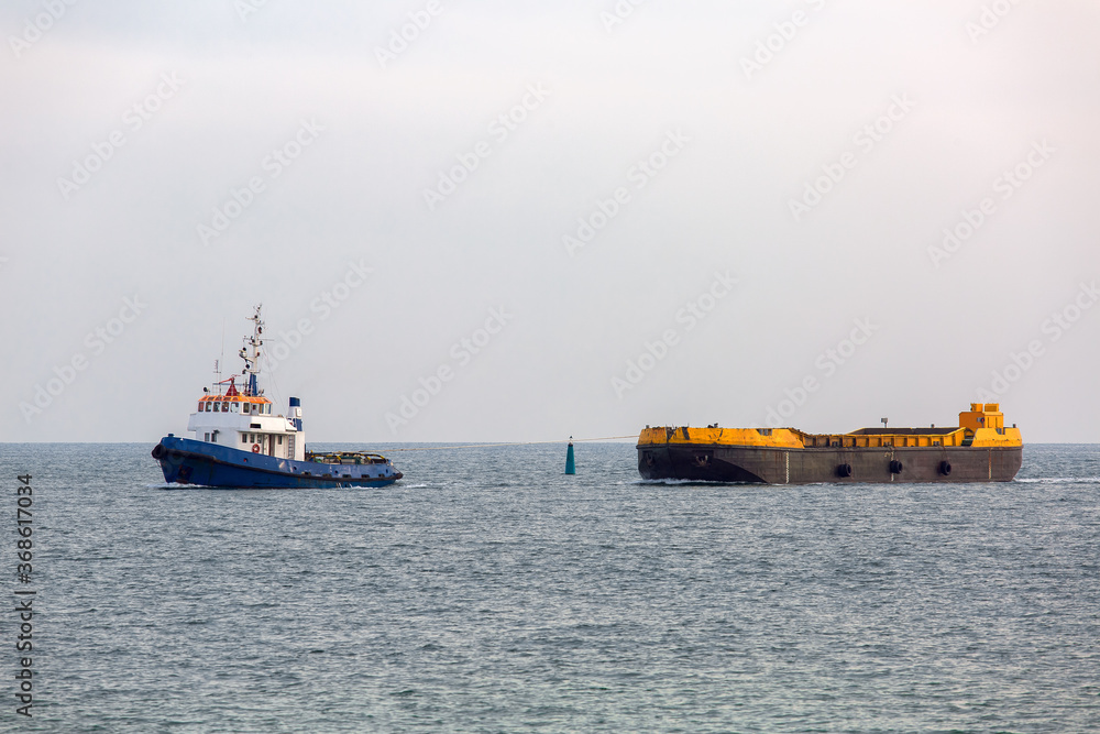 Fototapeta premium Tug rope pulls on the sea barge with sea sand.