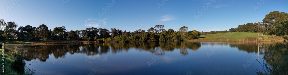 Beautiful morning panoramic view of a peaceful pond in a park with reflections of deep blue sky and tall trees, Fagan park, Galston, Sydney, New South Wales, Australia Beautiful morning panoramic view of a peaceful pond in a park with reflections of deep blue sky and tall trees, Fagan park, Galston, Sydney, New South Wales, Australia
