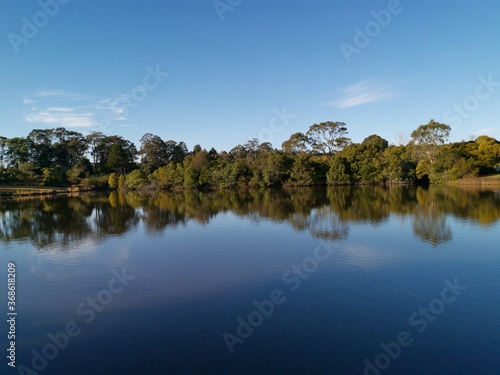 Beautiful morning view of a peaceful pond in a park with reflections of deep blue sky and tall trees, Fagan park, Galston, Sydney, New South Wales, Australia