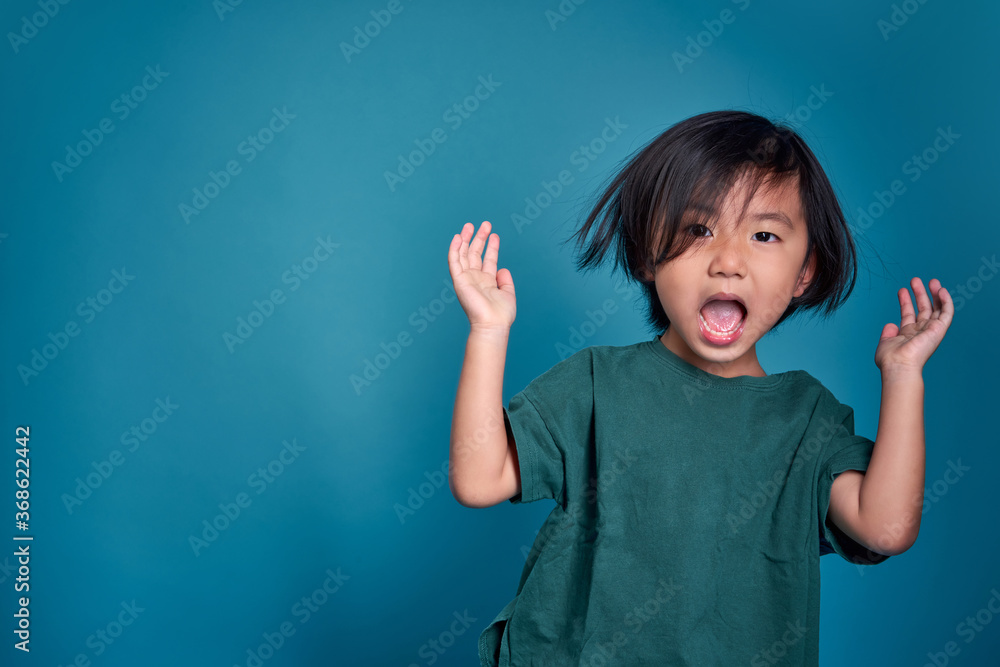 Beautiful asian little kid shouting or screaming. Empty space in studio shot isolated on colorful blue background. Education concept for school. Beautiful asian little kid shouting or screaming. Empty space in studio shot isolated on colorful blue background. Education concept for school.