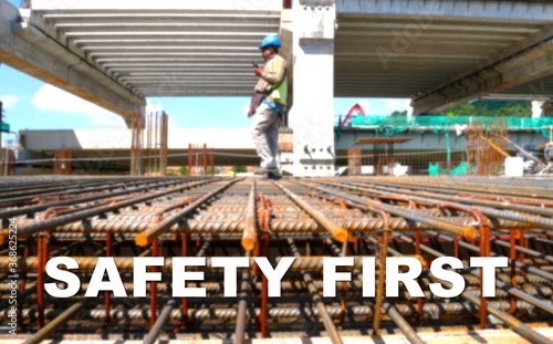 The word SAFETY FIRST is written clearly and against the background of the image of a worker installing a scaffolding. The image has been blurred.