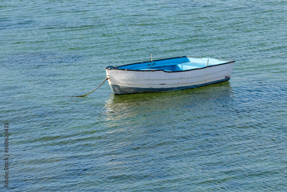 Naklejka premium wooden fishing boat with a motor anchored in the sea, calm natural landscape