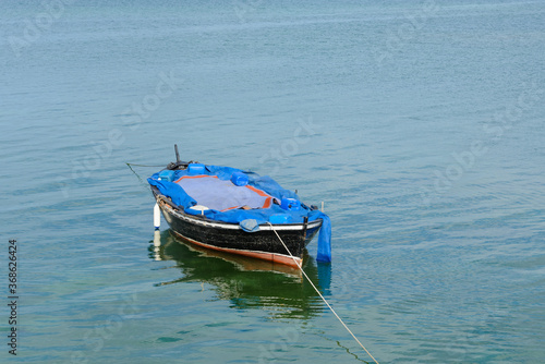 wooden fishing boat with a motor anchored in the sea, calm natural landscape © sergiy1975