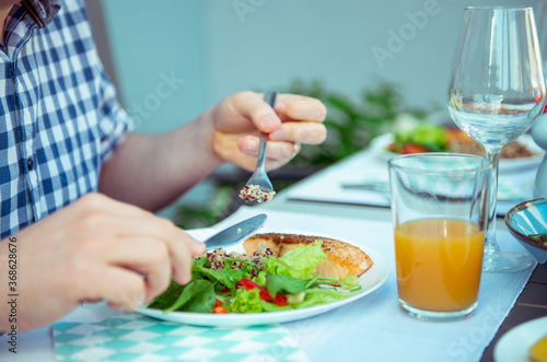 Close up photo of hands man eating salad  quinoa and fish on terrace