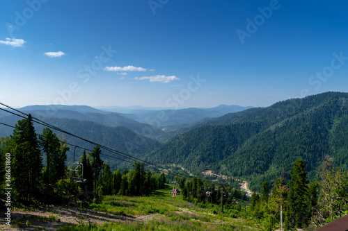 Altai, Russia - July 20, 2020. cable car chair lift in the mountains. climbing the mountain on a lift. beautiful view from the top of the mountain to the hills covered with coniferous forest