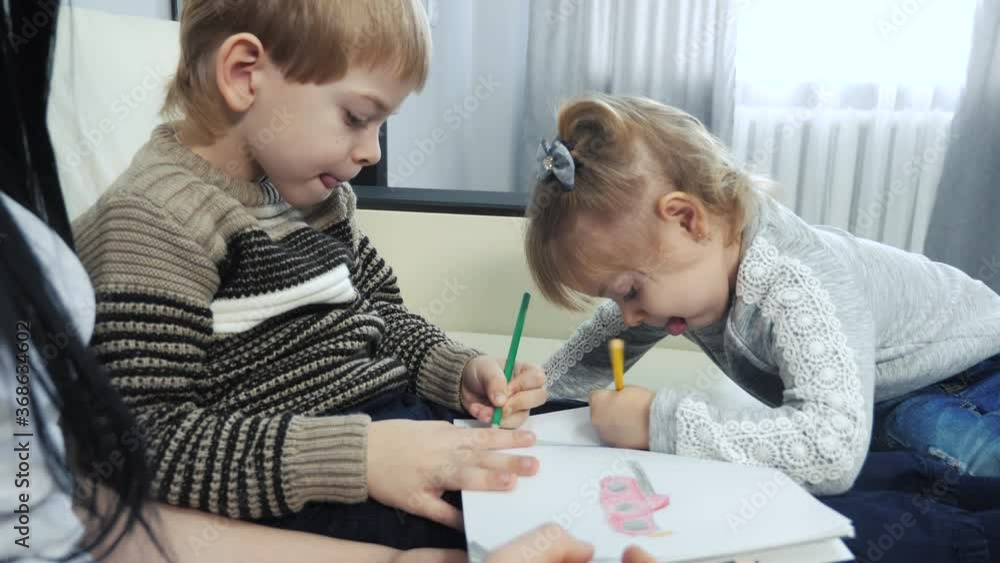little boy and girl and mom draw teamwork happy family concept. kids children son with are engaged in pencil lifestyle drawing. lesson with children development of creativity little boy and girl and mom draw teamwork happy family concept. kids children son with are engaged in pencil lifestyle drawing. lesson with children development of creativity