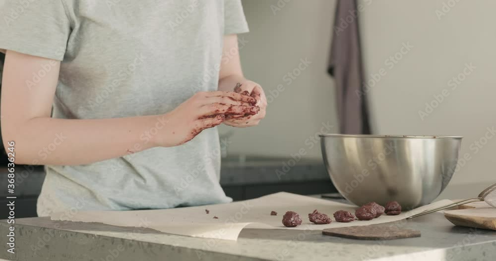 Slow motion shot of young woman making chocolate truffles on home kictchen Slow motion shot of young woman making chocolate truffles on home kictchen