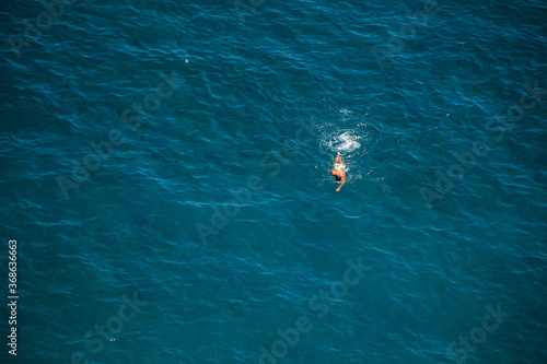 A man is swimming in the clear water of the Costiera Amalfitana