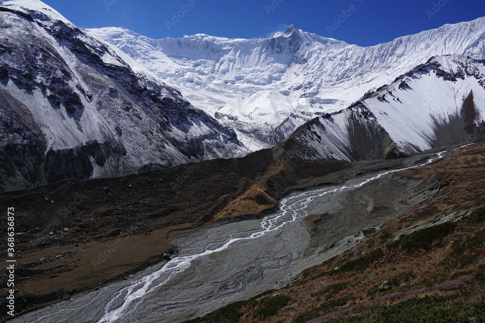 Khangsar Kang and other mountains in Annapurna Mountain range, its glacier, and the river flowing down Tilicho lake in Manang, Nepal.
