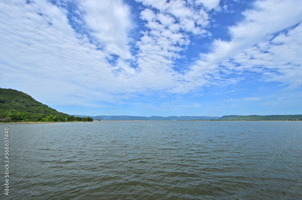 White clouds in blue sky and smooth waves in the water White clouds in blue sky and smooth waves in the water