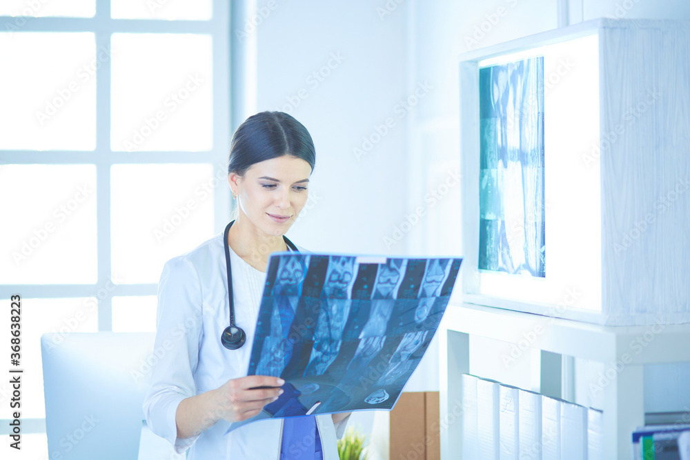 Young female doctor with stethoscope examining X-ray at doctor's office Young female doctor with stethoscope examining X-ray at doctor's office