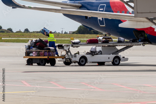 Billede på lærred Airport staff unload luggage from a plane.
