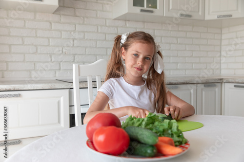 little girl in the kitchen cutting vegetables