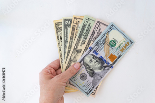 A stack of money American dollar bills lies in a female hand on a white background. The concept of buying for dollars