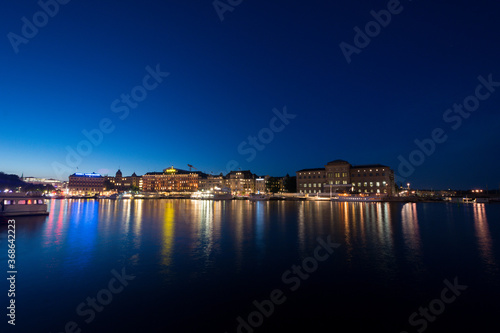 Illuminated skyline of the swedish city of Stockholm taken at night, the lights reflecting in the harbor's water. © Martin