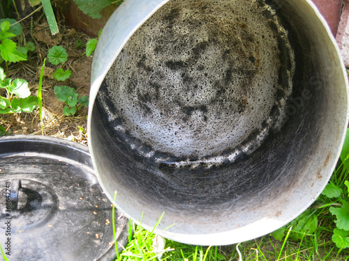 an old iron pot with a black lid is drying outside photo