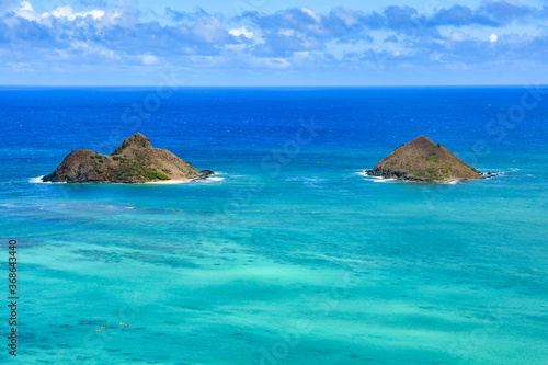 Light blue ocean water and two small islands. Blue sky with white clouds. Beautiful landscape of Oahu, Hawaii