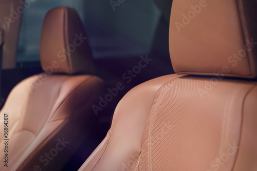 Expensive Brown leather car interior. Modern car illuminated dashboard. Luxurious car instrument cluster. Close up shot the seat of the car. Modern car interior dashboard. Soft light