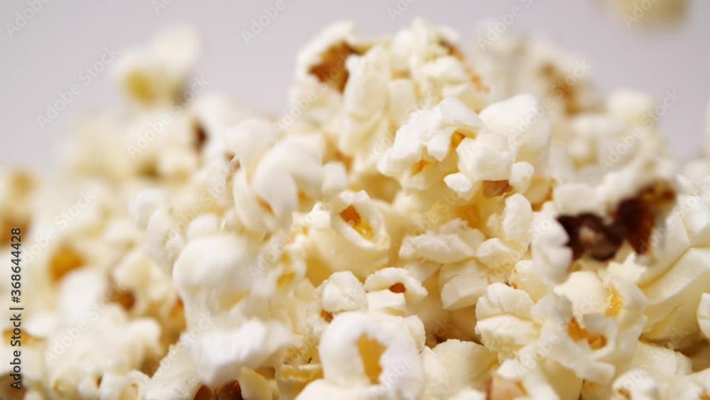 Closeup fresh yummy popcorn falling down in pile after preparation against gray background Closeup fresh yummy popcorn falling down in pile after preparation against gray background