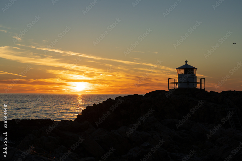 Lighthouse in silhouette with sunset over sea at Kullaberg nature reserve in Sweden. Popular tourist destination.