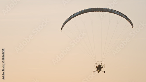 Silhouette of the Paramotor Tandem Gliding And Flying In The Air. Copy space High quality photo