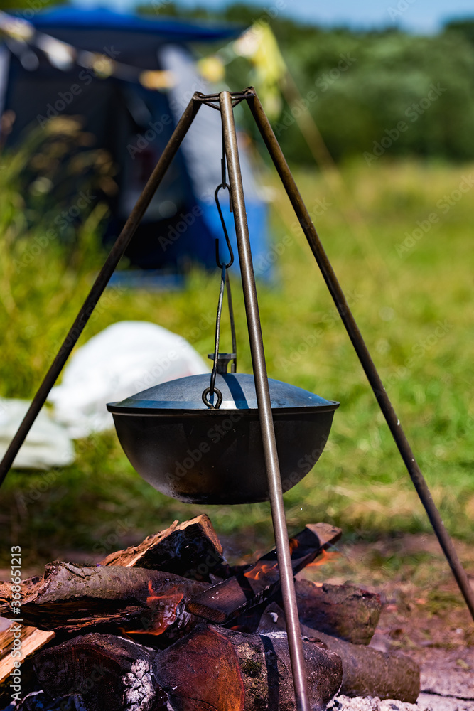 Camping bowler hat hangs over the fire on a tripod Camping bowler hat hangs over the fire on a tripod