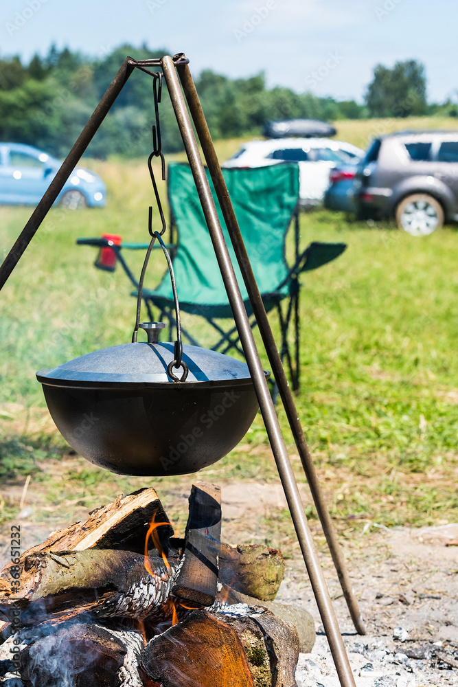 Camping bowler hat hangs over the fire on a tripod Camping bowler hat hangs over the fire on a tripod