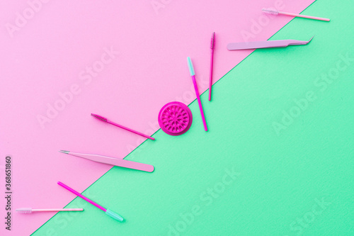 Flat lay style beauty business background.  Complementary colour palette of pink and teal green showing eyelash extension or lash artist tools and treatment products