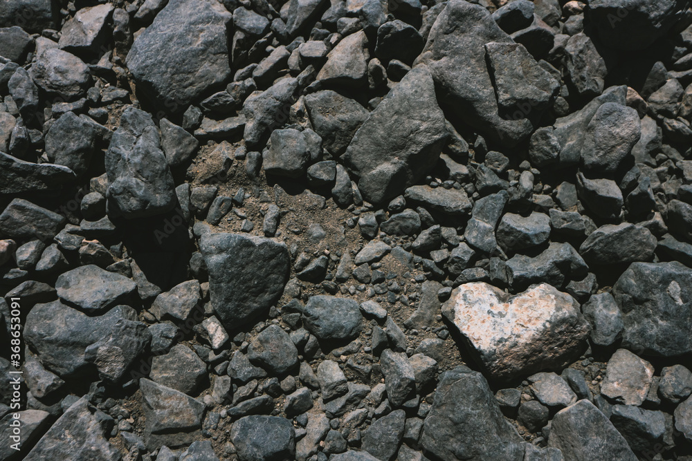 Heart shaped white stone among dark volcanic rocks background with copy space. Seen in Lanzarote, Canary Islands, Spain. 