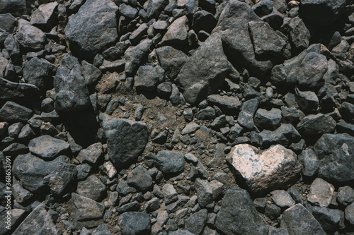Heart shaped white stone among dark volcanic rocks background with copy space. Seen in Lanzarote, Canary Islands, Spain. 