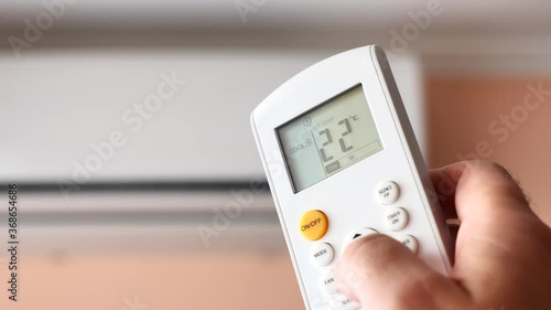 Split Air conditioner, Man operating remote controller	