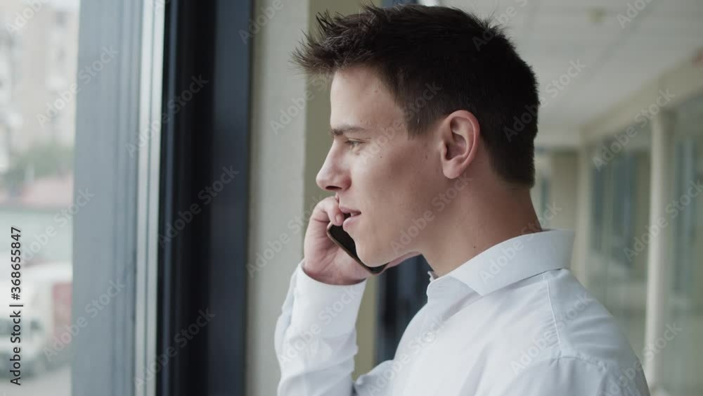 Profile of office manager talks on phone and drinks a cup of coffee in corridor Profile of office manager talks on phone and drinks a cup of coffee in corridor