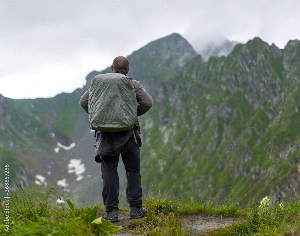 Hiker man with backpack on a mountain trail